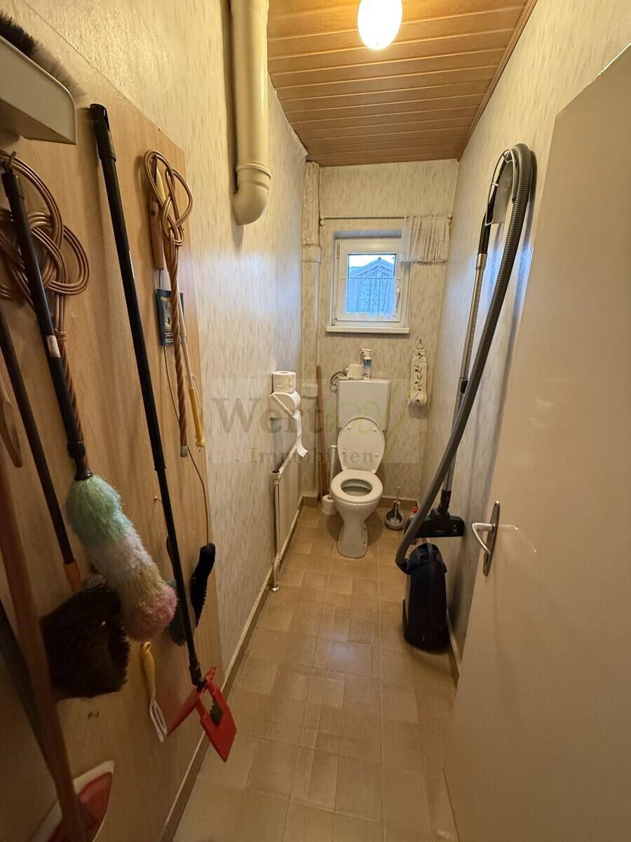 Separate Toilette mit Fenster, Fliesenboden und Heizkörper.