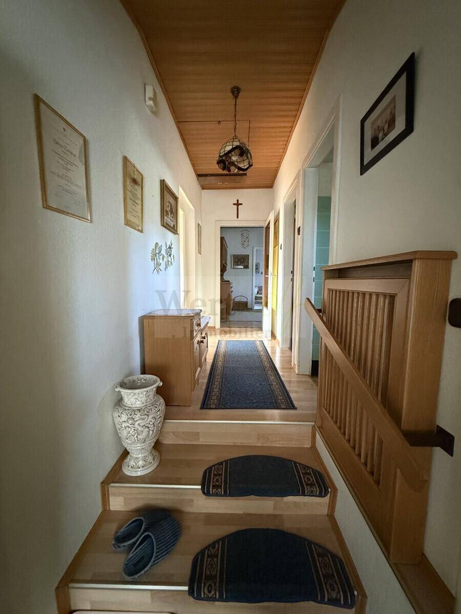 Treppenaufgang und Flur mit Holzdecke und Holztreppe, die zu den oberen Räumen führt.