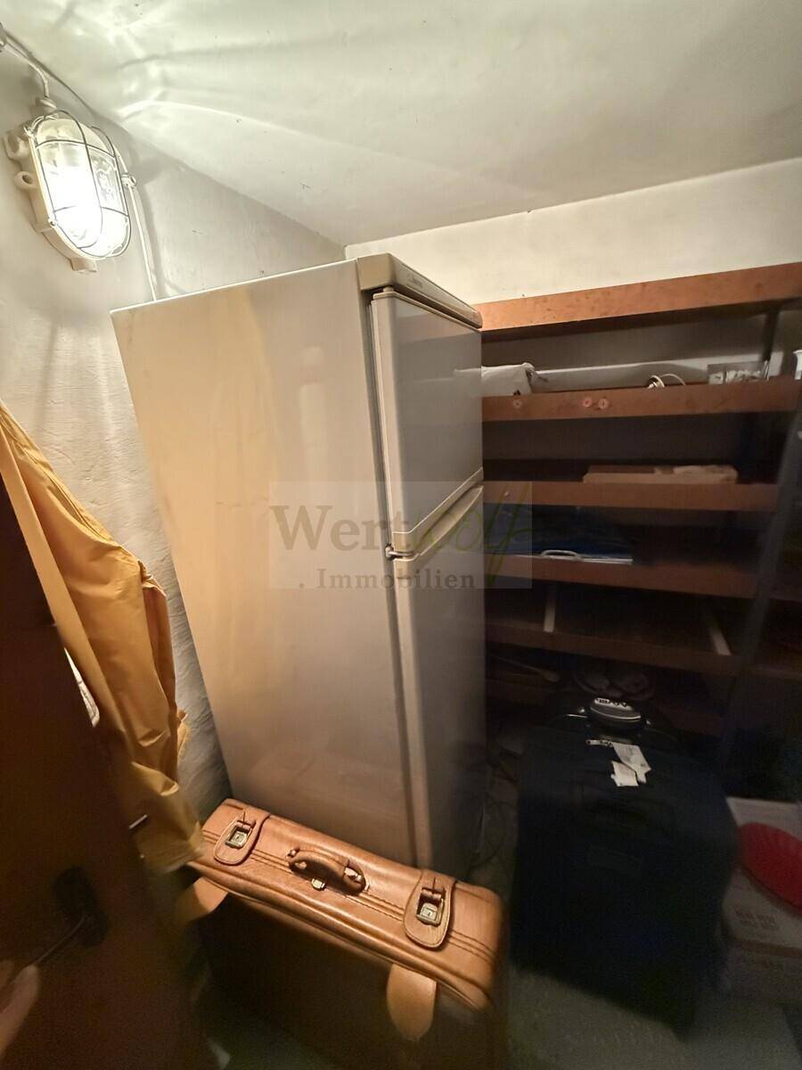 Kellerraum mit einem großen Kühlschrank und Regalen für zusätzliche Lagerung.