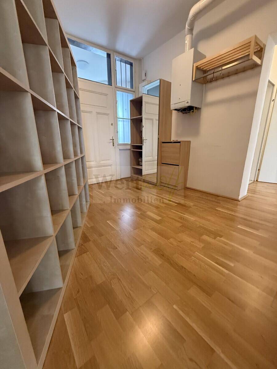 Eingangsbereich mit Holzregal, Spiegel, Garderobe und Heiztherme, bietet praktischen Stauraum.