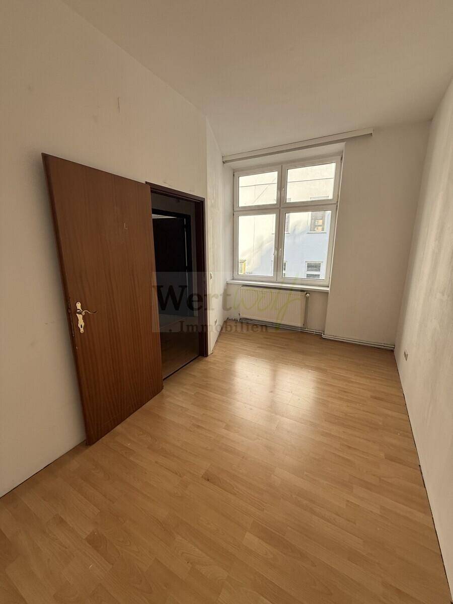 Helles Schlafzimmer mit Laminatboden und Fenster, ideal für individuelle Gestaltung.