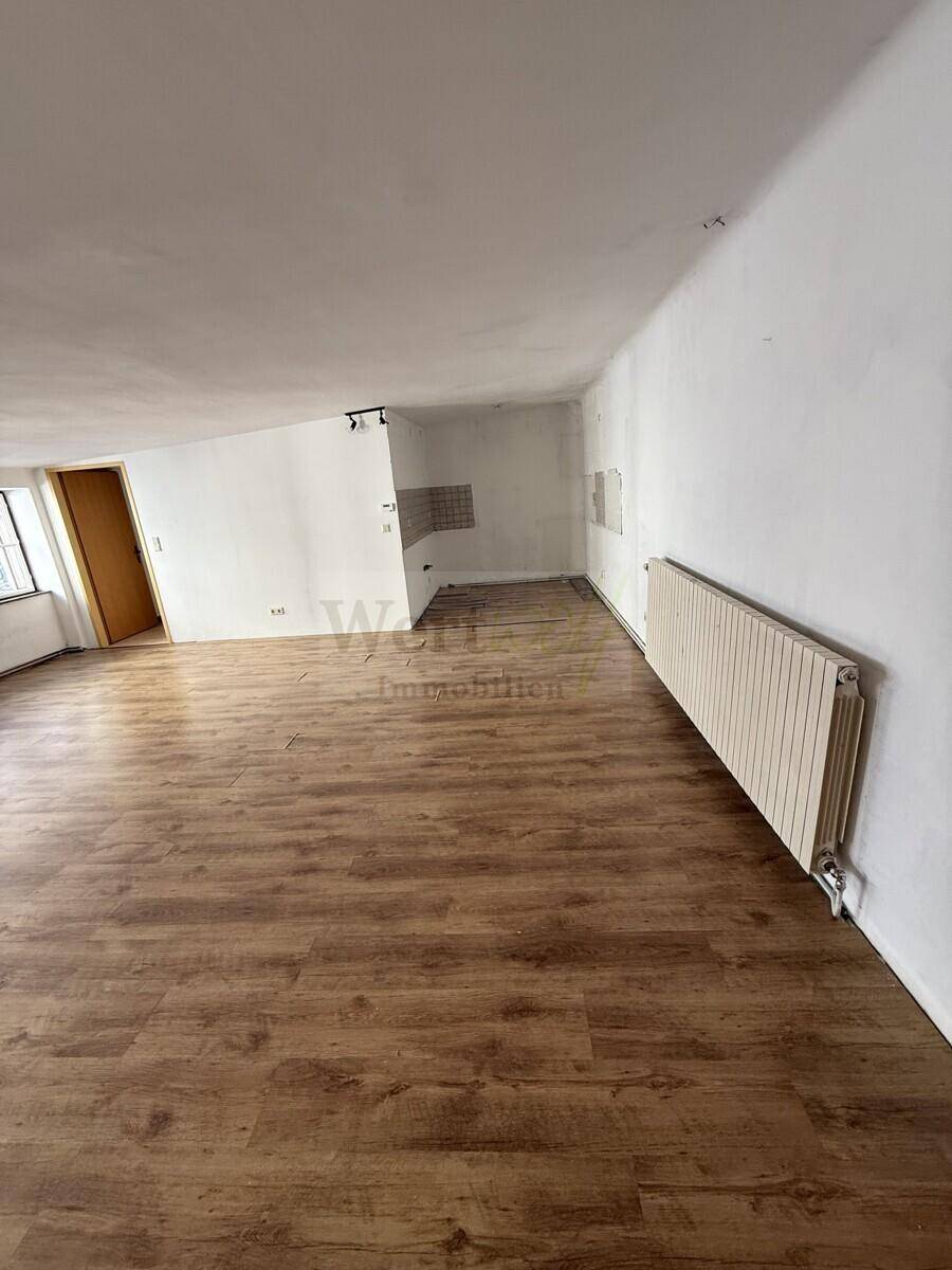 Geräumiger Raum mit Laminatboden und einer Nische für die zukünftige Kücheninstallation.