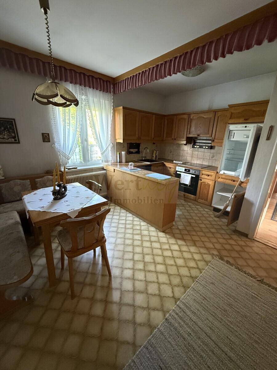 Gemütliche Wohnküche mit Holzschränken, Essbereich und traditionellen Bodenfliesen.