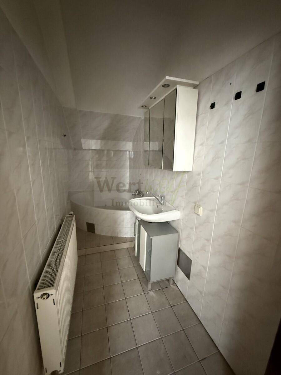 Badezimmer mit Fliesen, Waschbeckenunterschrank und integrierter Badewanne.