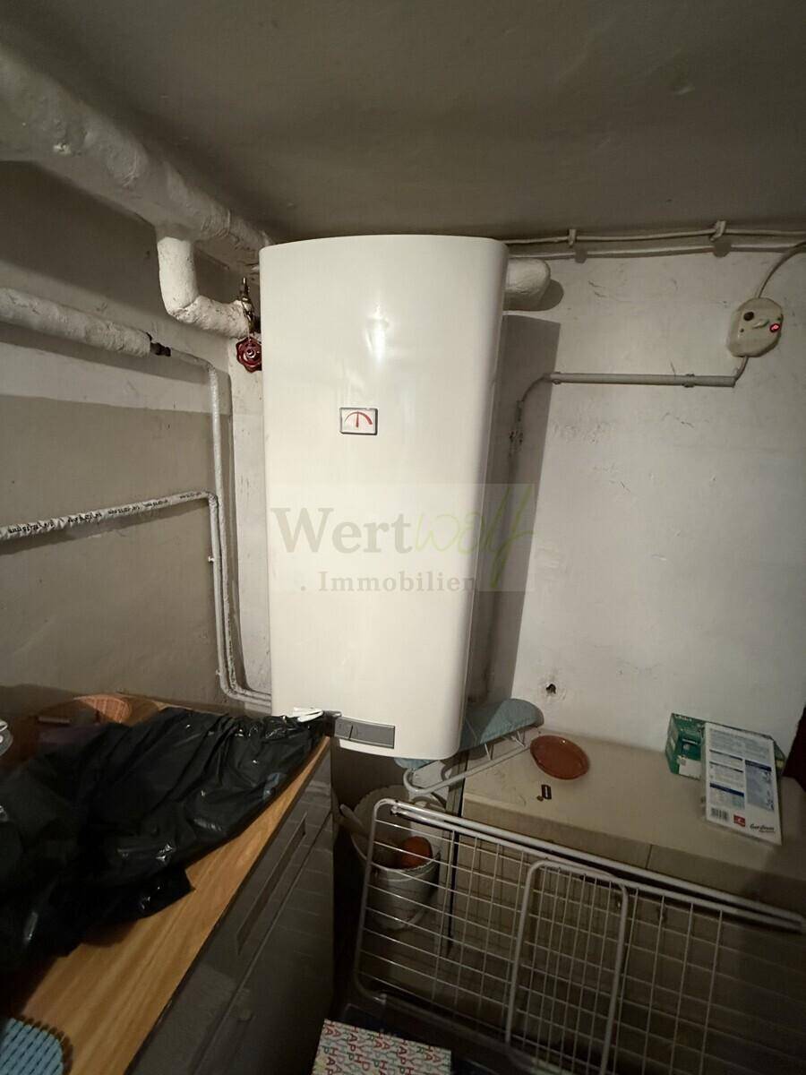 Heizungsraum im Keller mit einem modernen Heizkessel und sichtbaren Installationen.