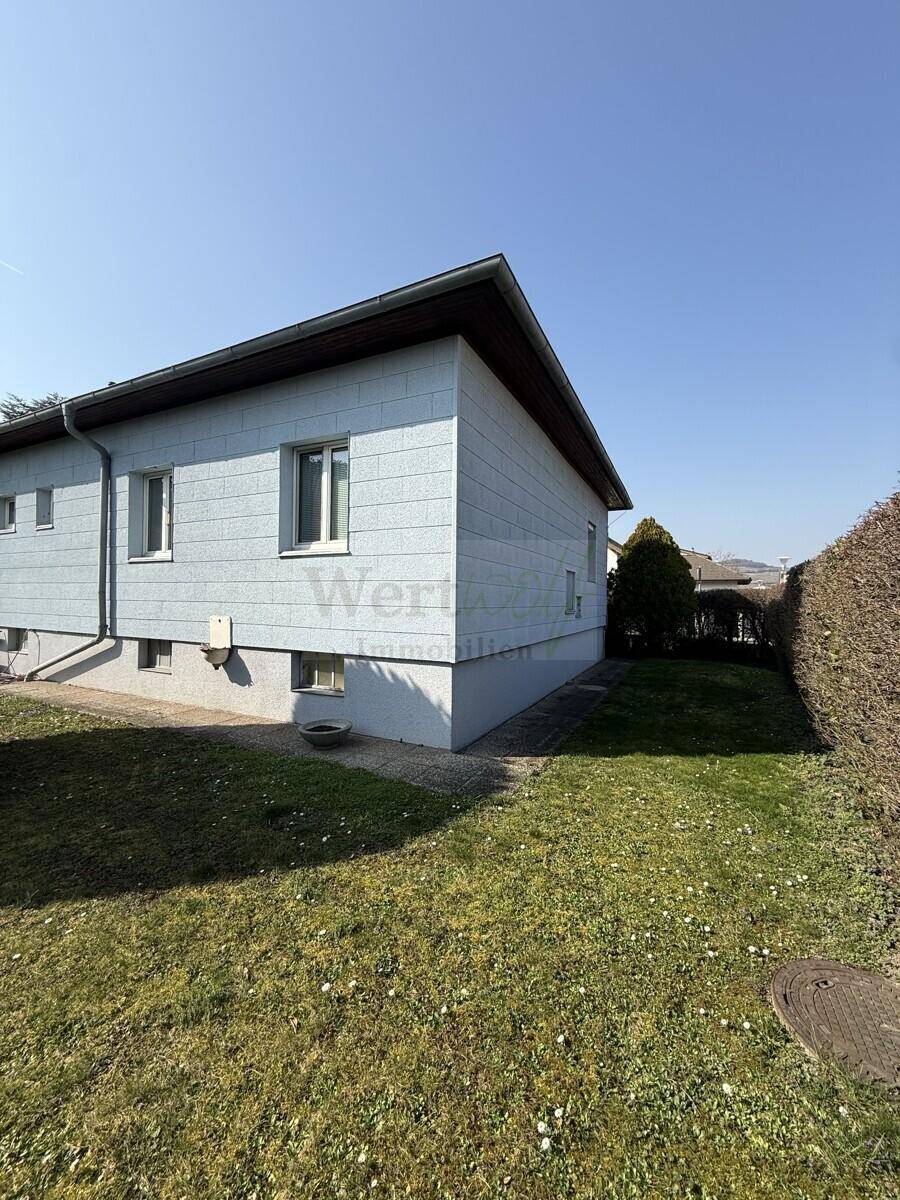 Seitenansicht des Hauses mit hellblauer Fassade und einem gepflegten Rasenbereich.