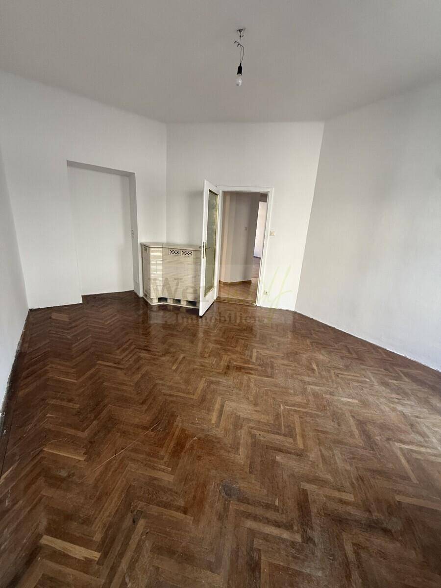 Geräumiges Zimmer mit klassischem Fischgrätparkettboden und weißen Wänden, bereit zur individuellen Gestaltung.