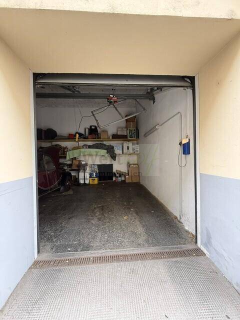 Einzelgarage mit Regalablagen und einem Garagentor-Öffner.