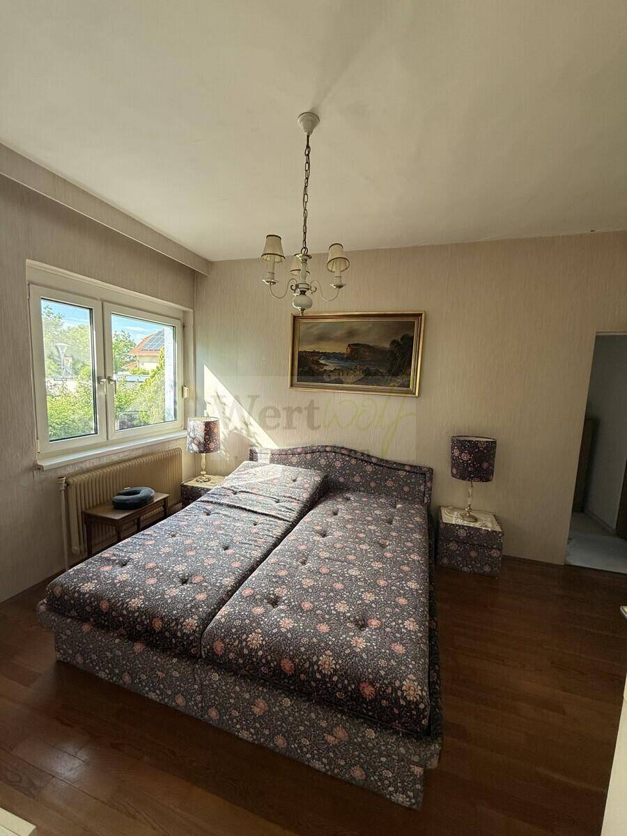 Helles Schlafzimmer mit zwei Einzelbetten, Holzboden und Blick ins Grüne durch das Fenster.