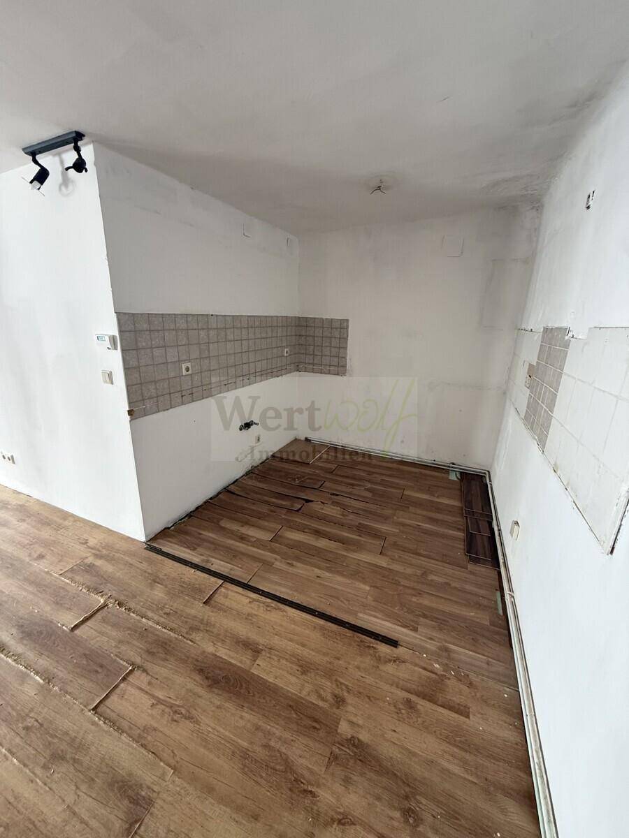 Bereich für eine Küche mit Fliesenrückwand und vorbereiteten Anschlüssen.