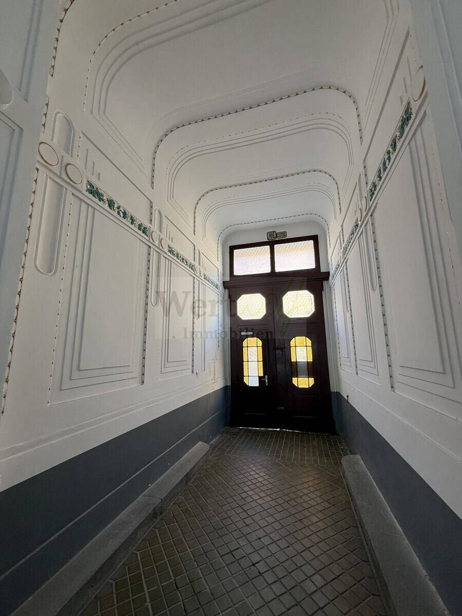 Detailansicht des historischen Flurs mit dekorativen Wandpaneelen und einer eleganten Holztür am Ende.