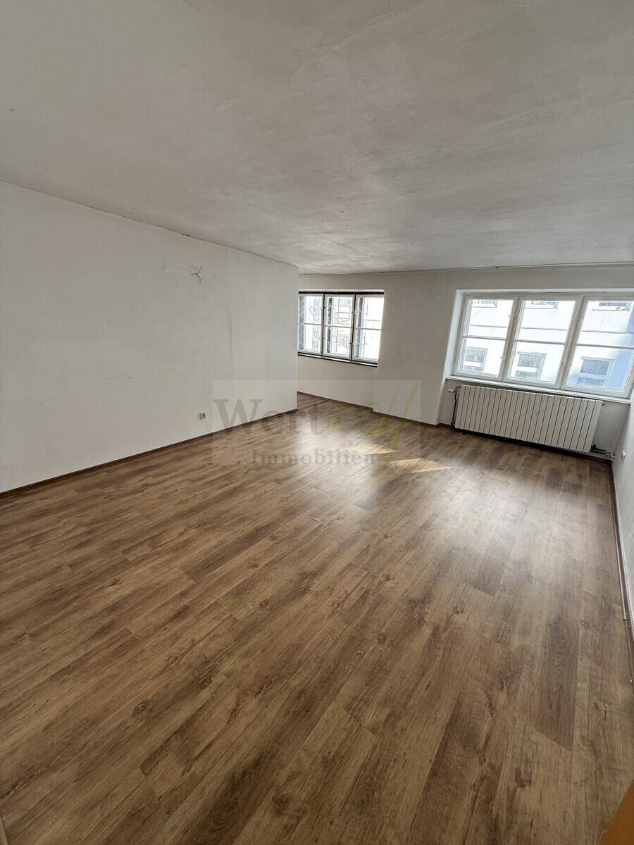 Geräumiger, heller Raum mit Laminatboden und mehreren Fenstern, bereit zur individuellen Gestaltung.