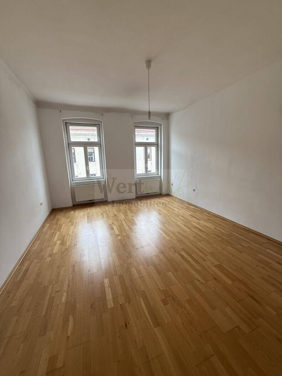 Ruhiges Schlafzimmer mit Parkettboden und zwei Fenstern, bietet viel natürliches Licht.