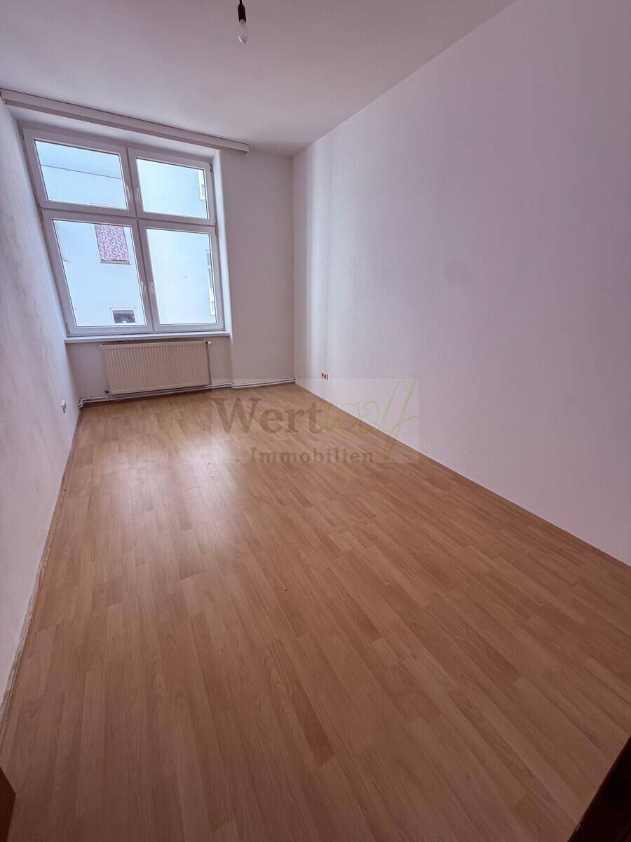 Helles Zimmer mit Laminatboden und weiß gestrichenen Wänden, bereit zur Einrichtung.