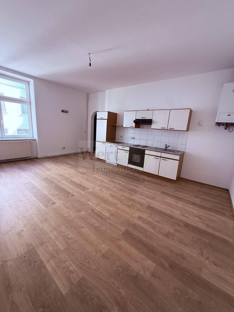 Kombinierter Wohn- und Essbereich mit funktionaler Küchenzeile und Blick nach draußen.