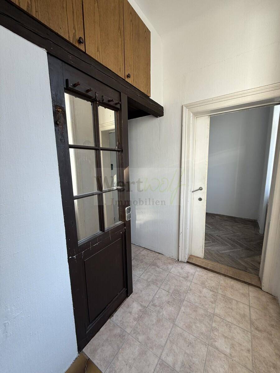 Eingangsbereich mit Fliesenboden und einer Holztür, die zu weiteren Räumen führt.