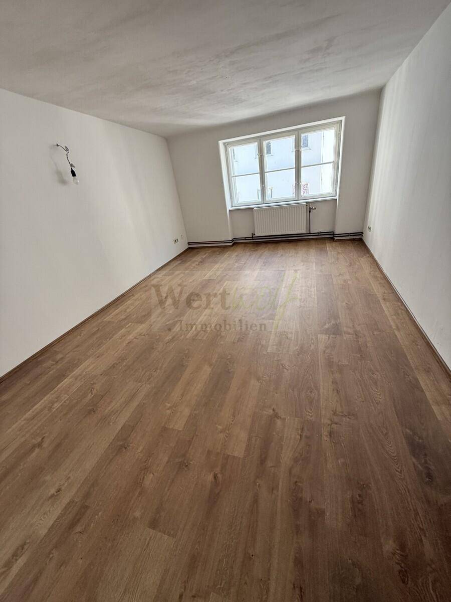 Helles Zimmer mit Laminatboden und einem großen Fenster, ideal als Schlaf- oder Arbeitszimmer.
