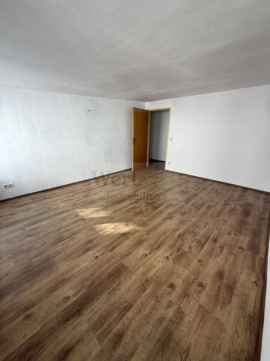 Heller Wohnraum mit Laminatboden und weiß gestrichenen Wänden, ideal für neue Einrichtungsideen.