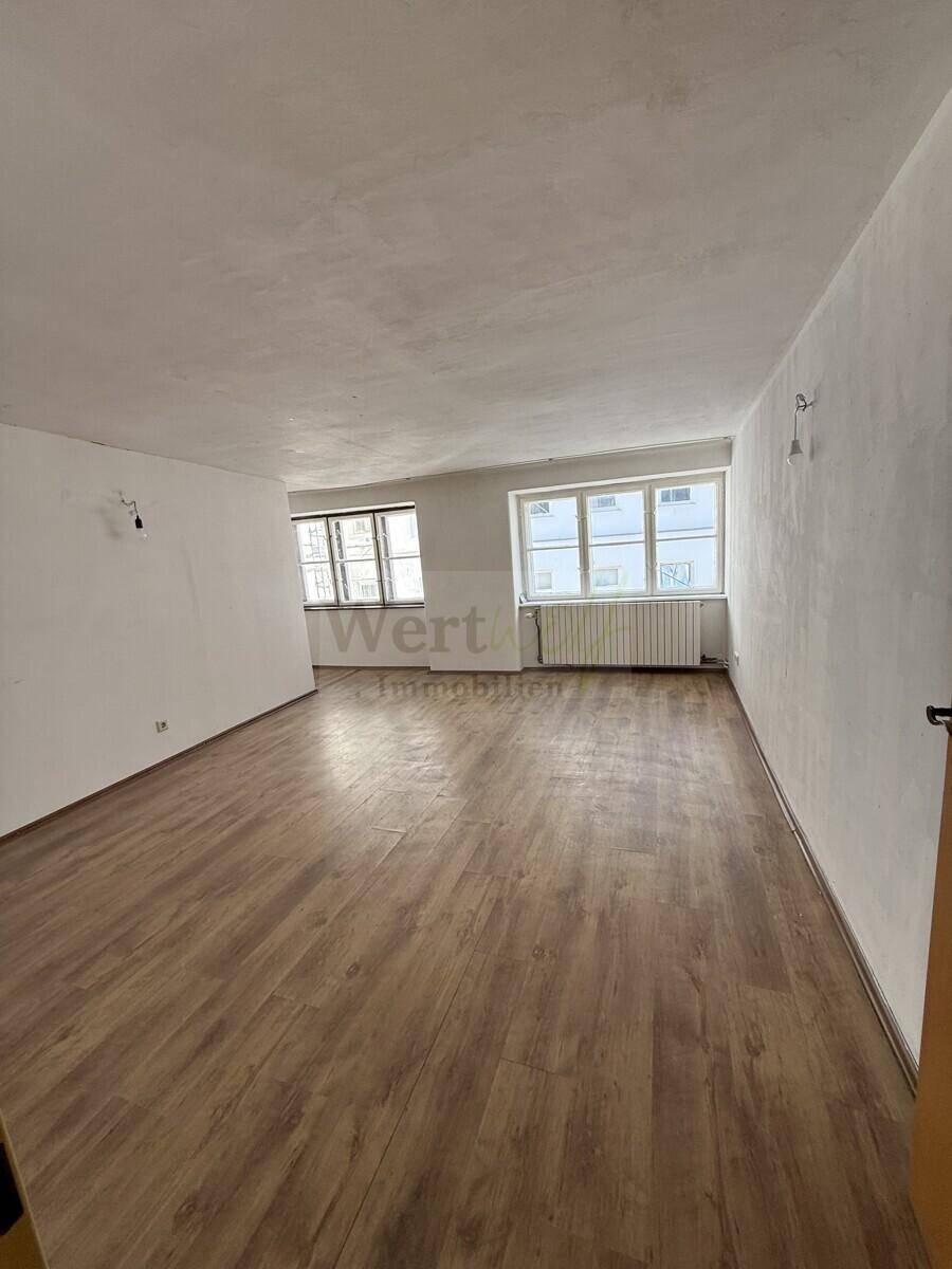 Großer, heller Raum mit Laminatboden und mehreren Fenstern, vielseitig nutzbar.