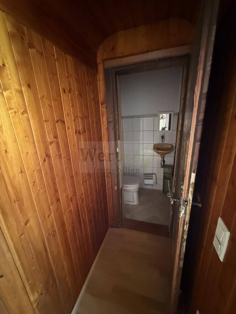 Kleines Gäste-WC mit Fliesenboden und Wandfliesen, ausgestattet mit einem Waschbecken und Toilette.