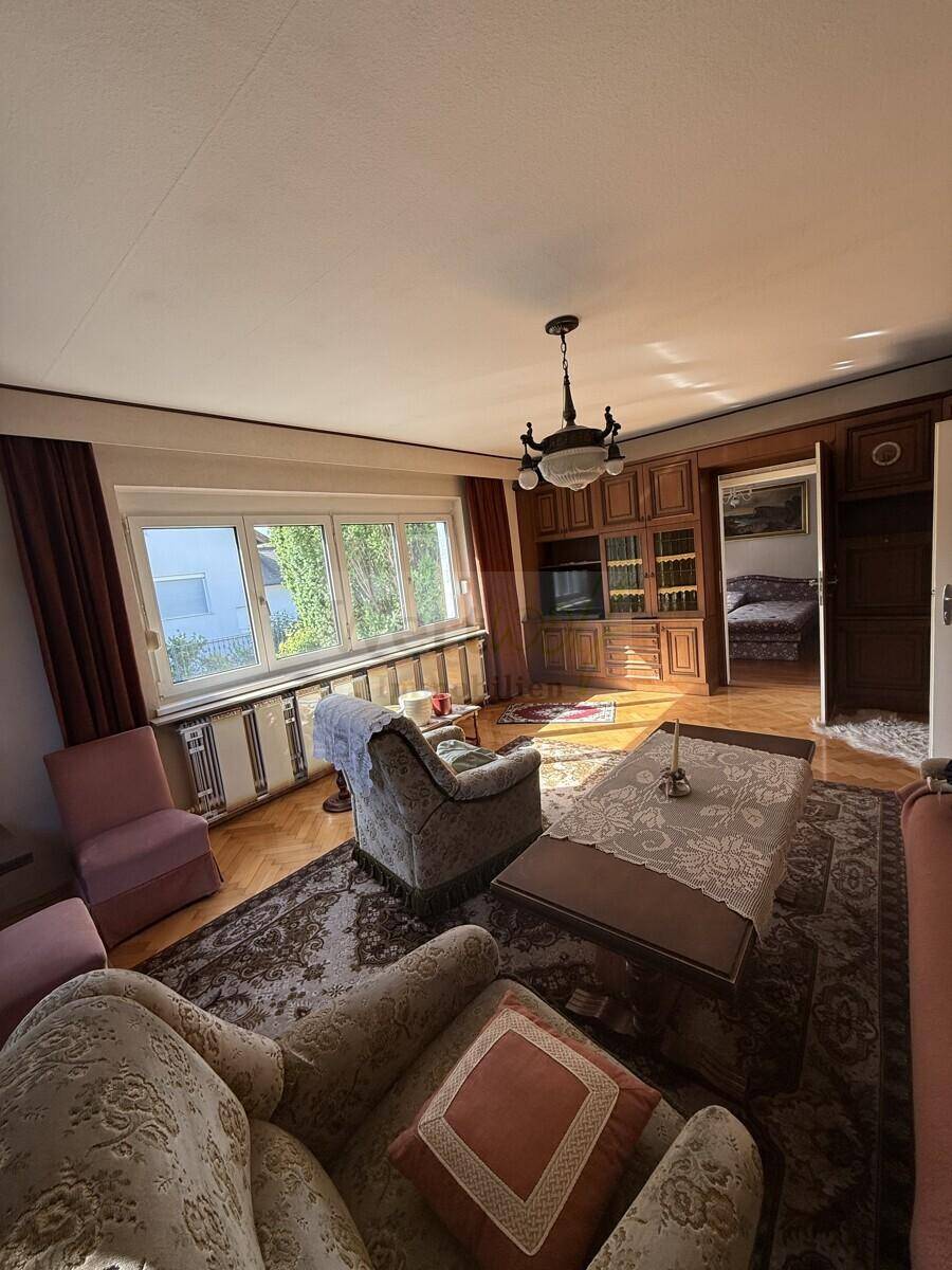 Gemütliches Wohnzimmer mit Parkettboden, Sofa und einem großen Einbauschrank aus Holz.