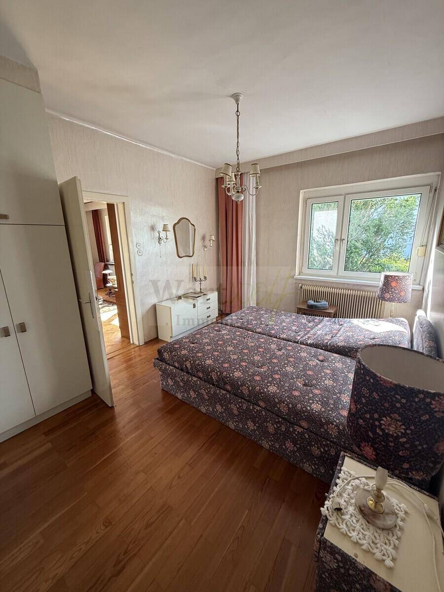 Geräumiges Schlafzimmer mit zwei Einzelbetten, Parkettboden und großem Fenster für viel Licht.