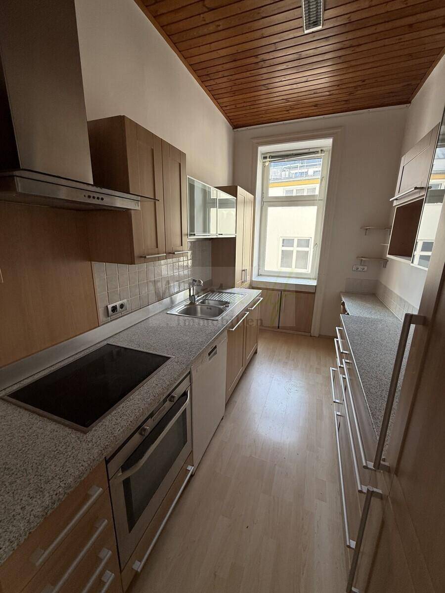 Funktionale Küche mit Holzschränken, Granitarbeitsplatte und integrierten Geräten, bereit zum Kochen.