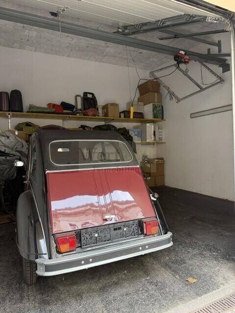 Gut gepflegte Garage mit einem klassischen Auto, Regalen und einem automatischen Garagentor.