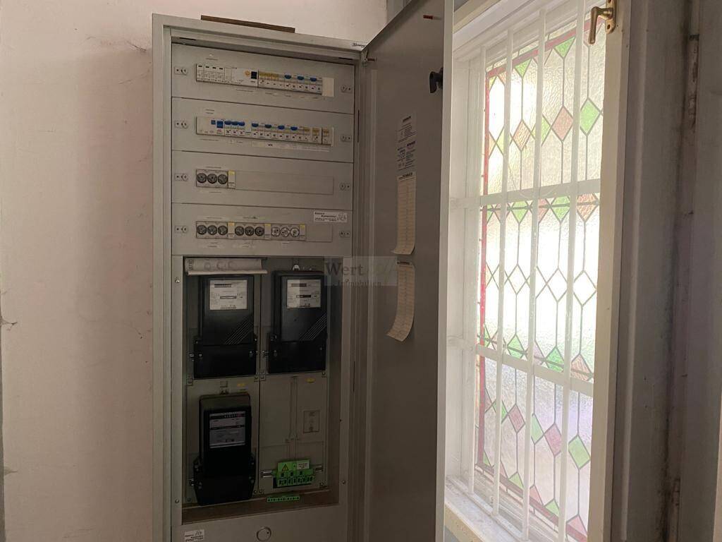 Großer Zählerschrank mit mehreren Stromzählern und Verkabelung neben einem Fenster.