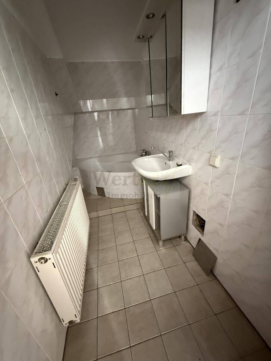 Gefliestes Badezimmer mit Badewanne, Waschbecken und Spiegelschrank.