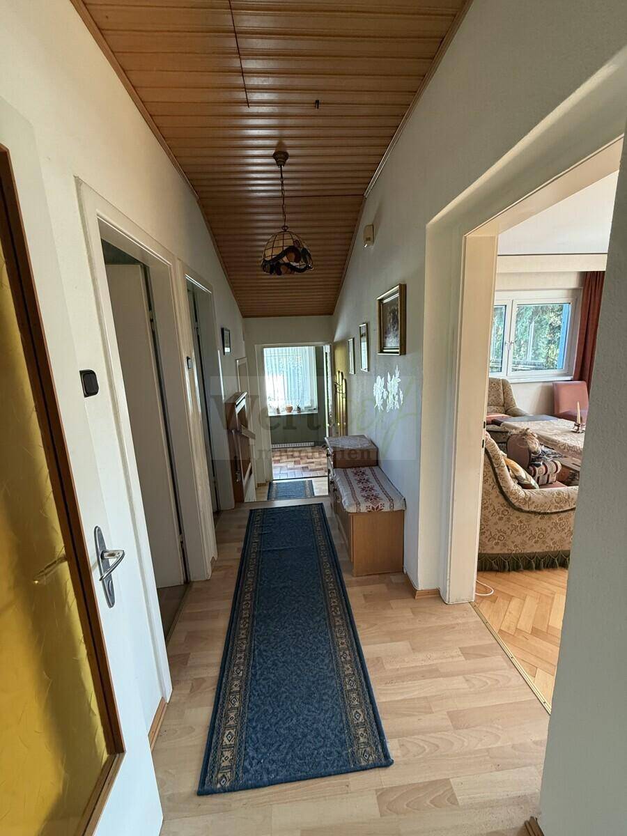 Langer Flur mit Holzdecke und Laminatboden, der verschiedene Zimmer miteinander verbindet.