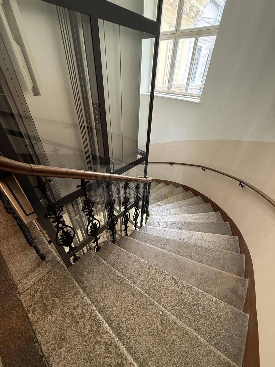 Detailansicht der Wendeltreppe mit Steinstufen und dem modernen Aufzugsschacht.