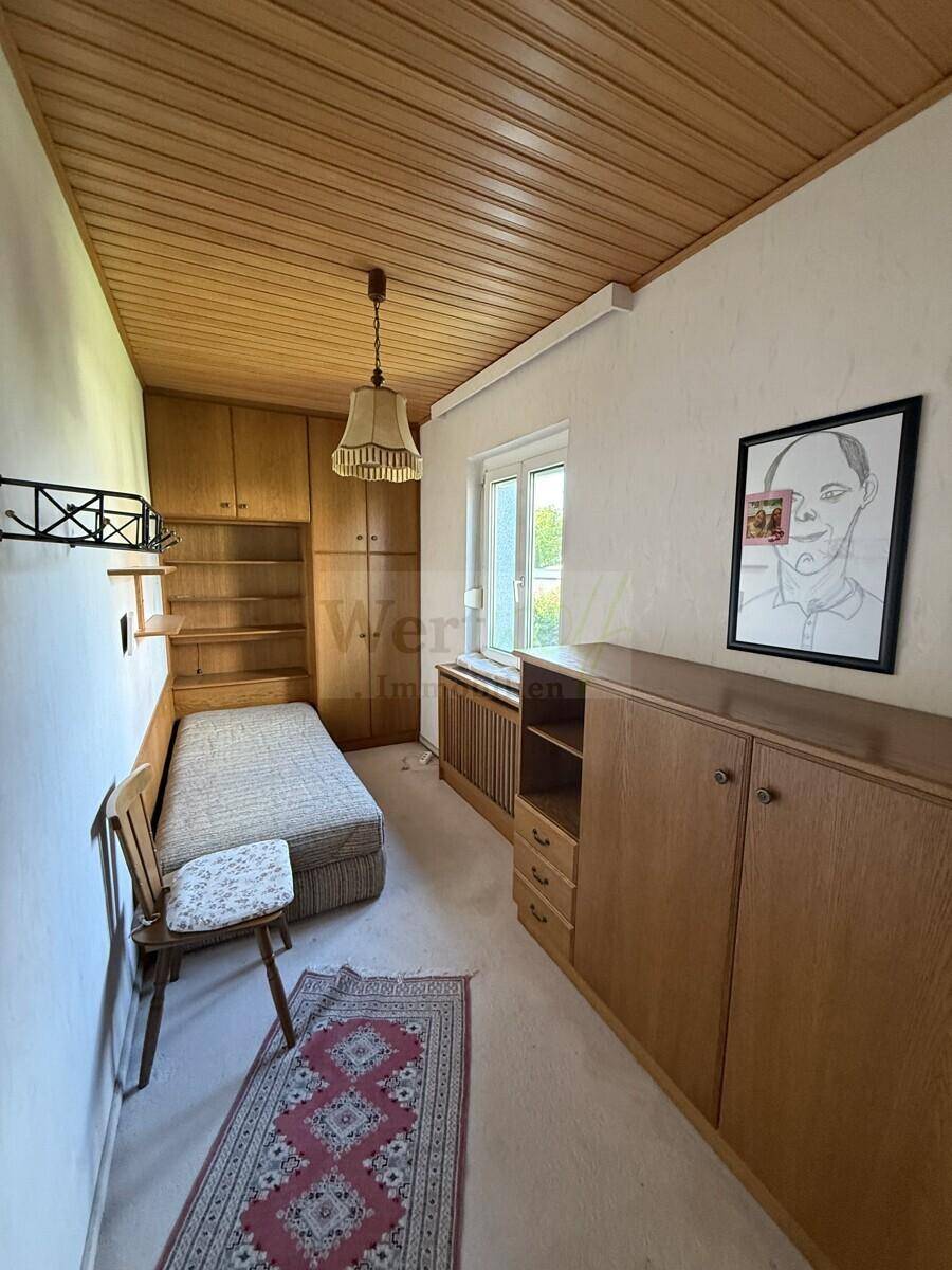 Schlafzimmer mit Einzelbett, Einbauschränken aus Holz und einer gemütlichen Holzdecke.