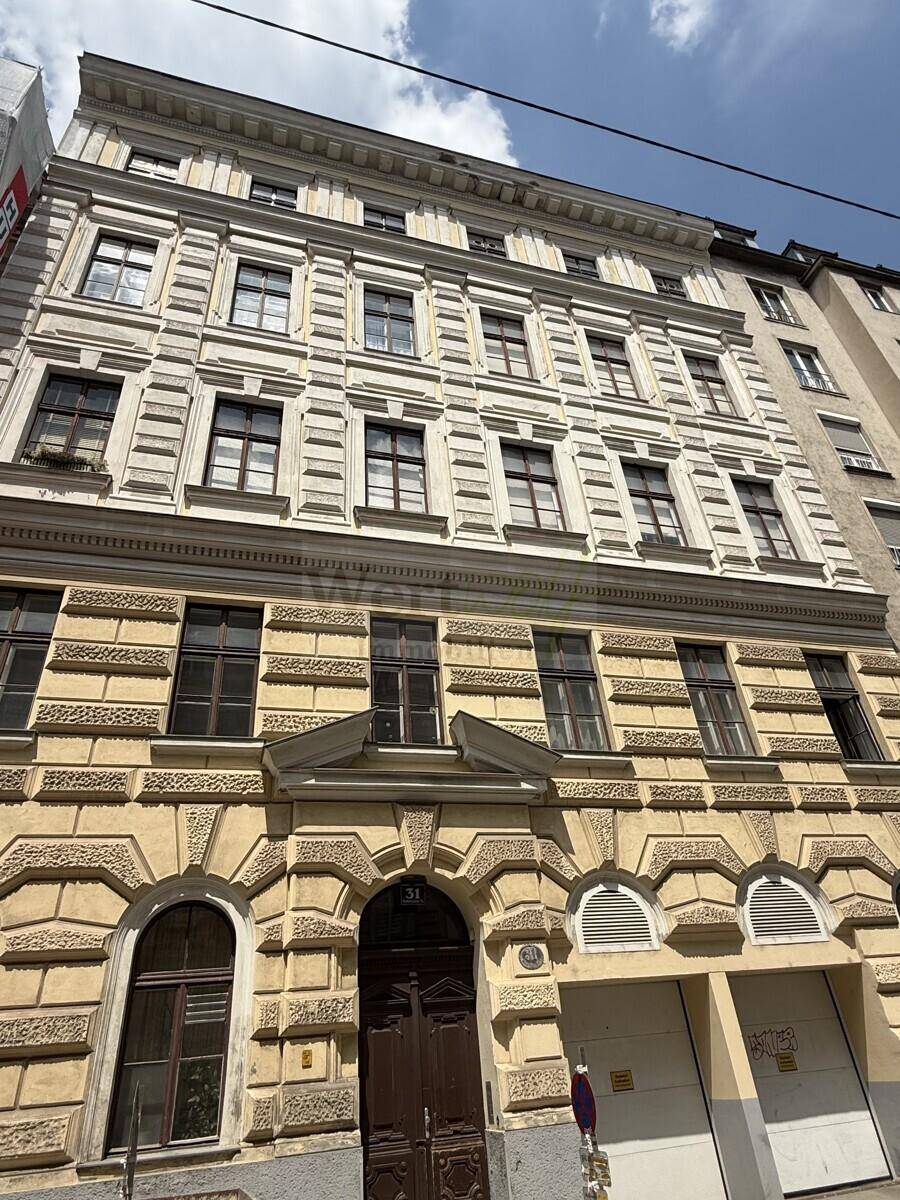 Detailreiche Fassade eines Altbaus mit vielen Fenstern und klassischer Architektur.