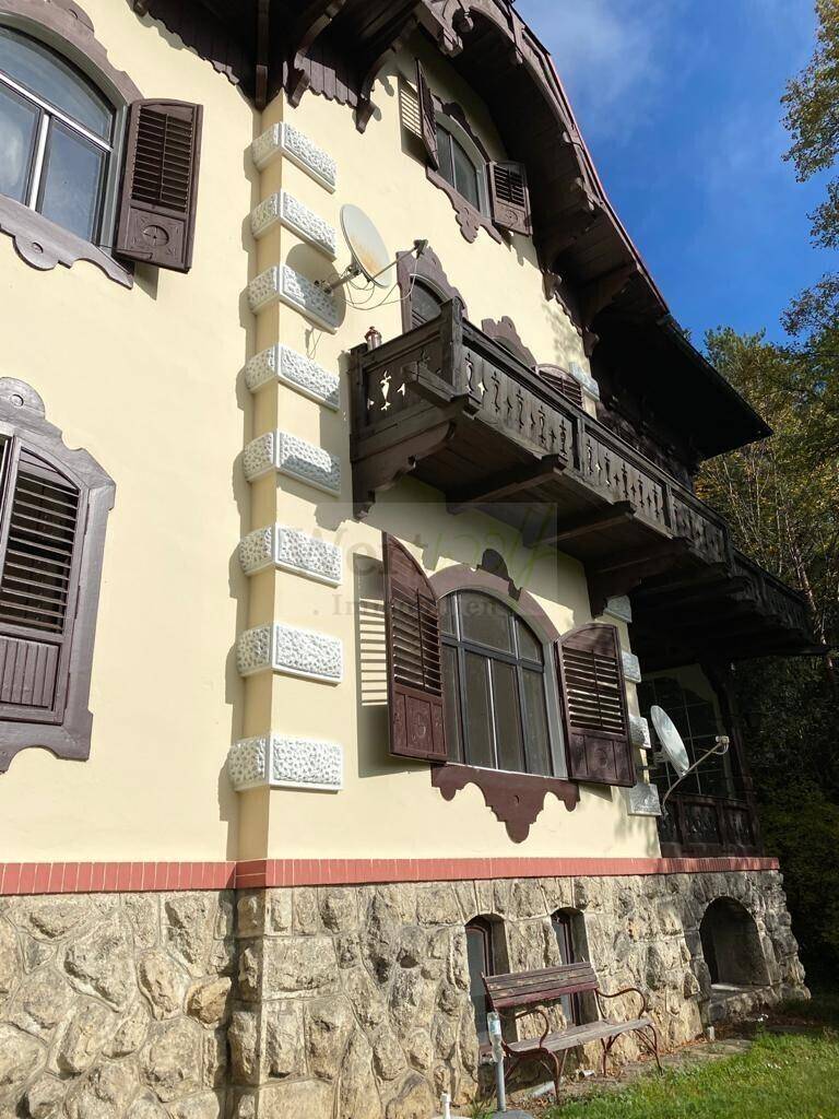 Detail der historischen Fassade mit verzierten Holzbalkonen, Fensterläden und Steinmauerwerk.