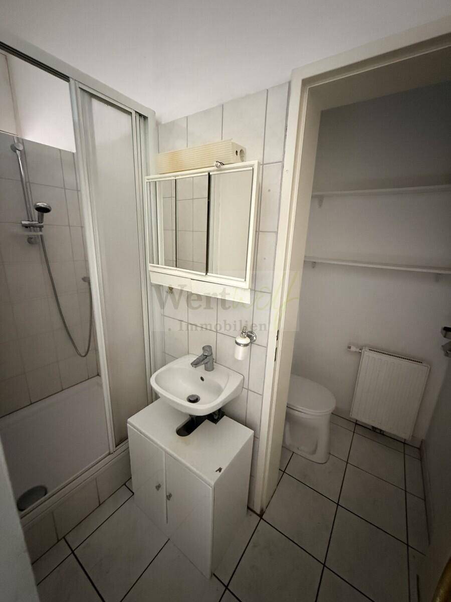 Badezimmer mit Duschwanne, Waschbecken und Spiegelschrank, in einem funktionalen Design.