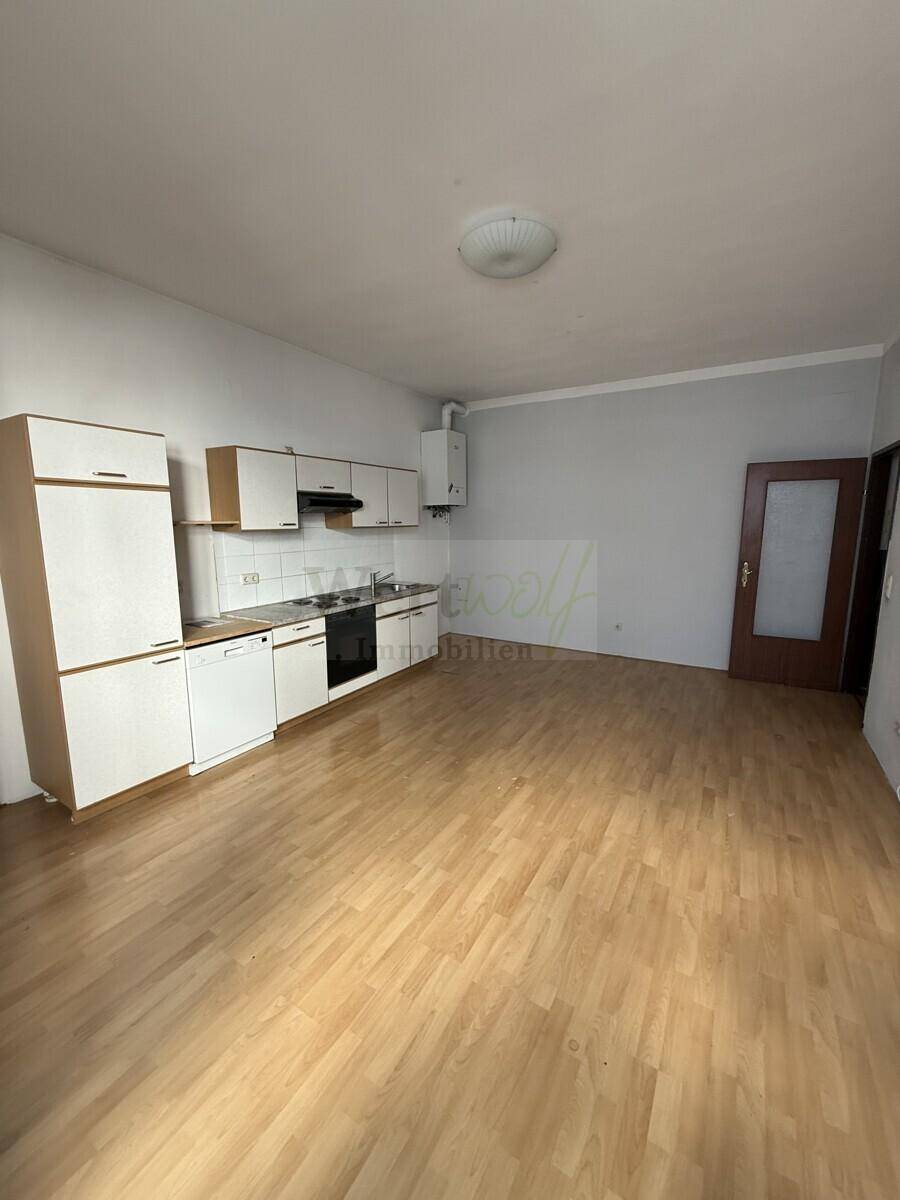 Funktionale Küche mit Einbauschränken, Spülmaschine und hellem Laminatboden.