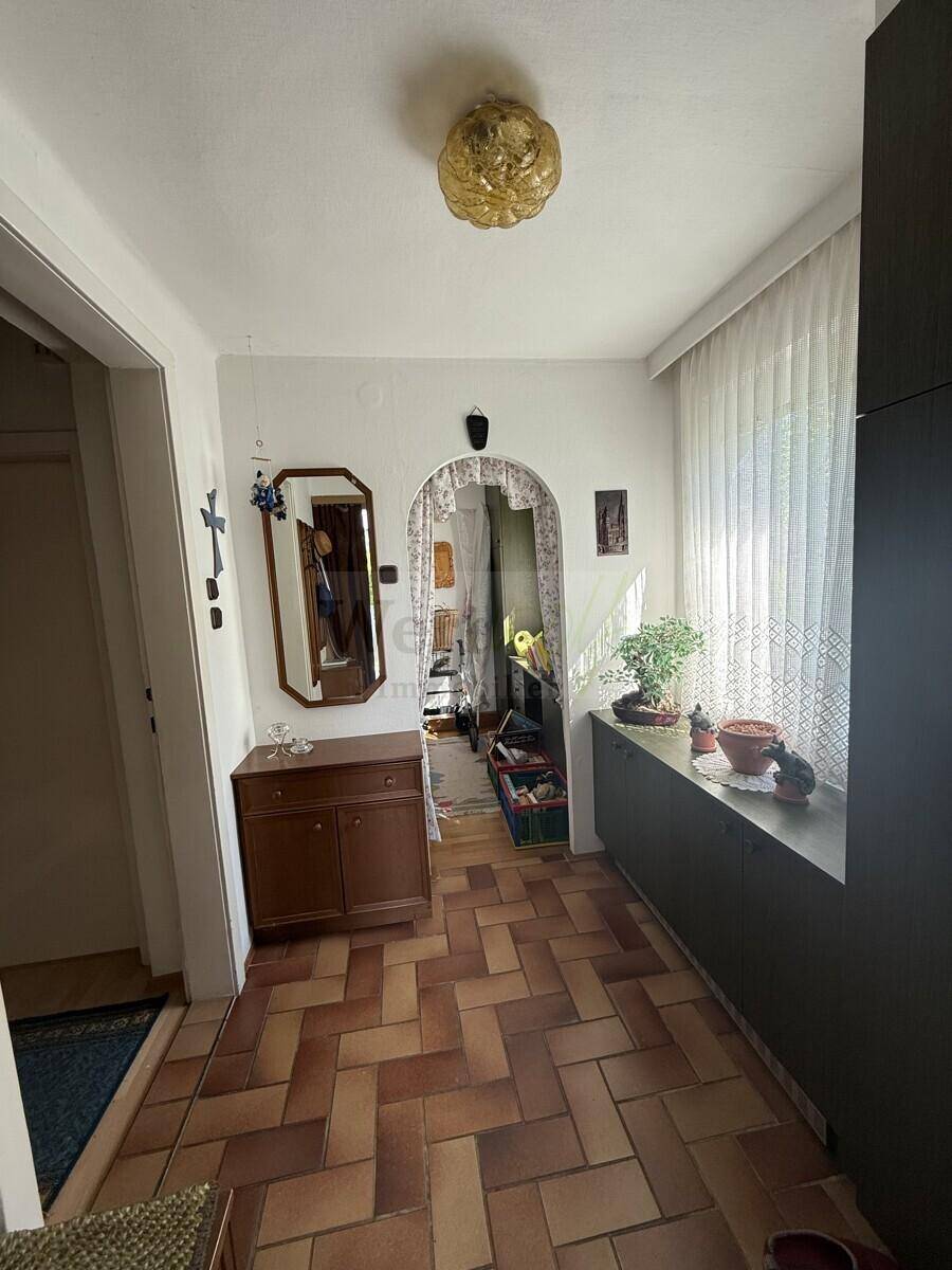 Heller Eingangsbereich mit Terrakotta-Fliesenboden, Spiegel und einem dekorativen Torbogen.