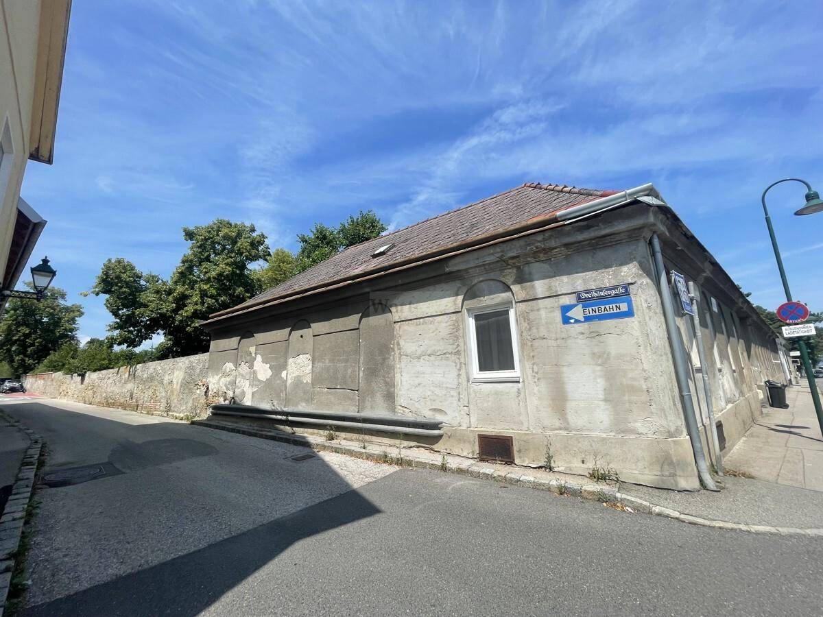 Seitenansicht des historischen Gebäudes an der Straße mit einem Straßenschild und alter Mauer.