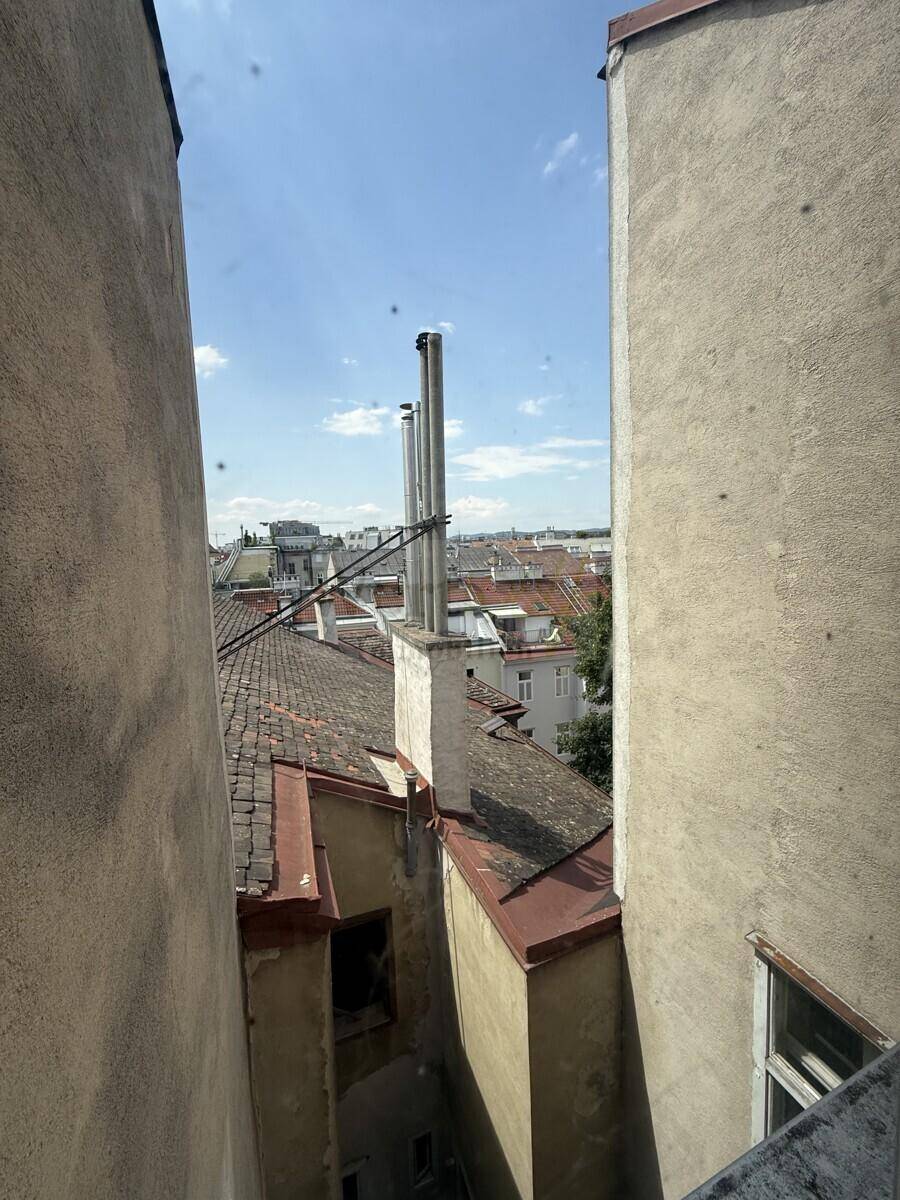 Blick über die Dächer der Stadt mit Schornsteinen und blauem Himmel.