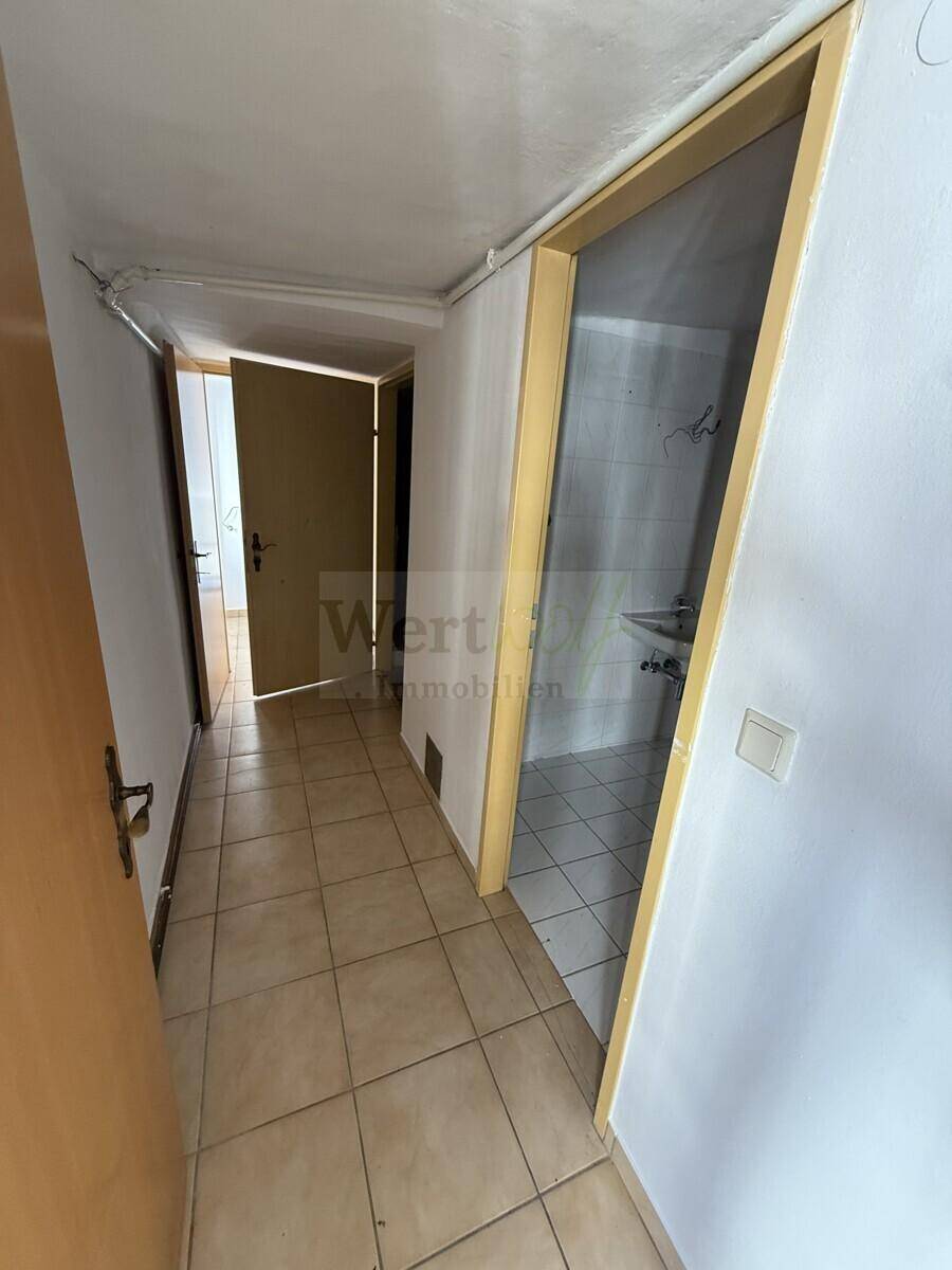Heller Flur mit Fliesenboden, der zu den angrenzenden Badezimmern führt.