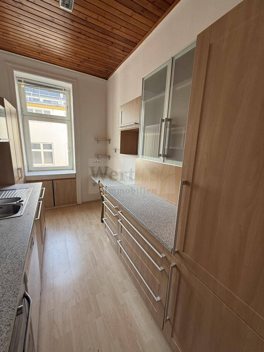 Moderne Küche mit hellen Holzfronten, Granitarbeitsplatte und ausreichend Stauraum für Küchenutensilien.