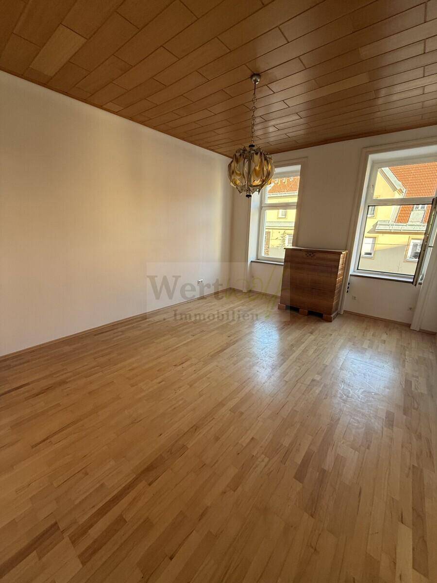 Großes, helles Zimmer mit Parkettboden und Holzdecke, das vielseitig nutzbar ist und eine angenehme Wohnatmosphäre bietet.