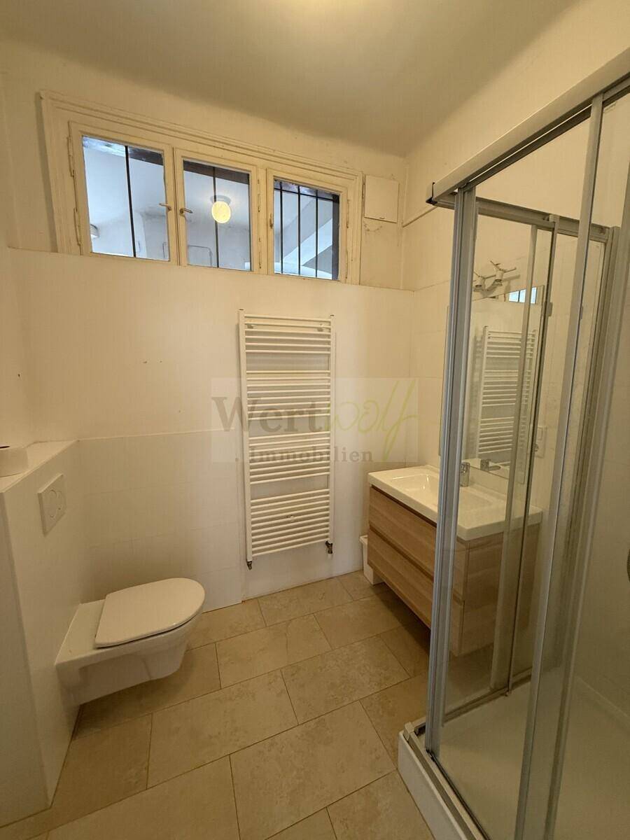 Modernes Badezimmer mit Dusche, WC, Waschbecken und beheiztem Handtuchhalter.