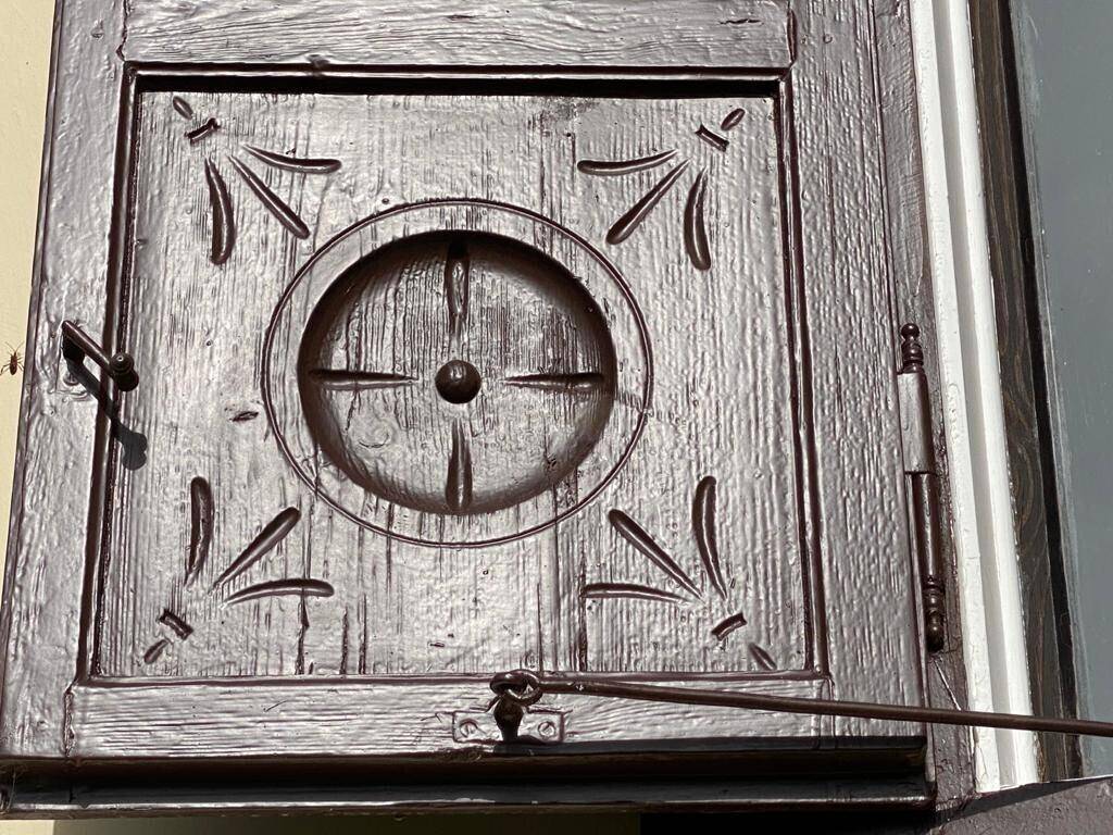 Detailansicht eines traditionellen Holzfensterladens mit geschnitzten Verzierungen.