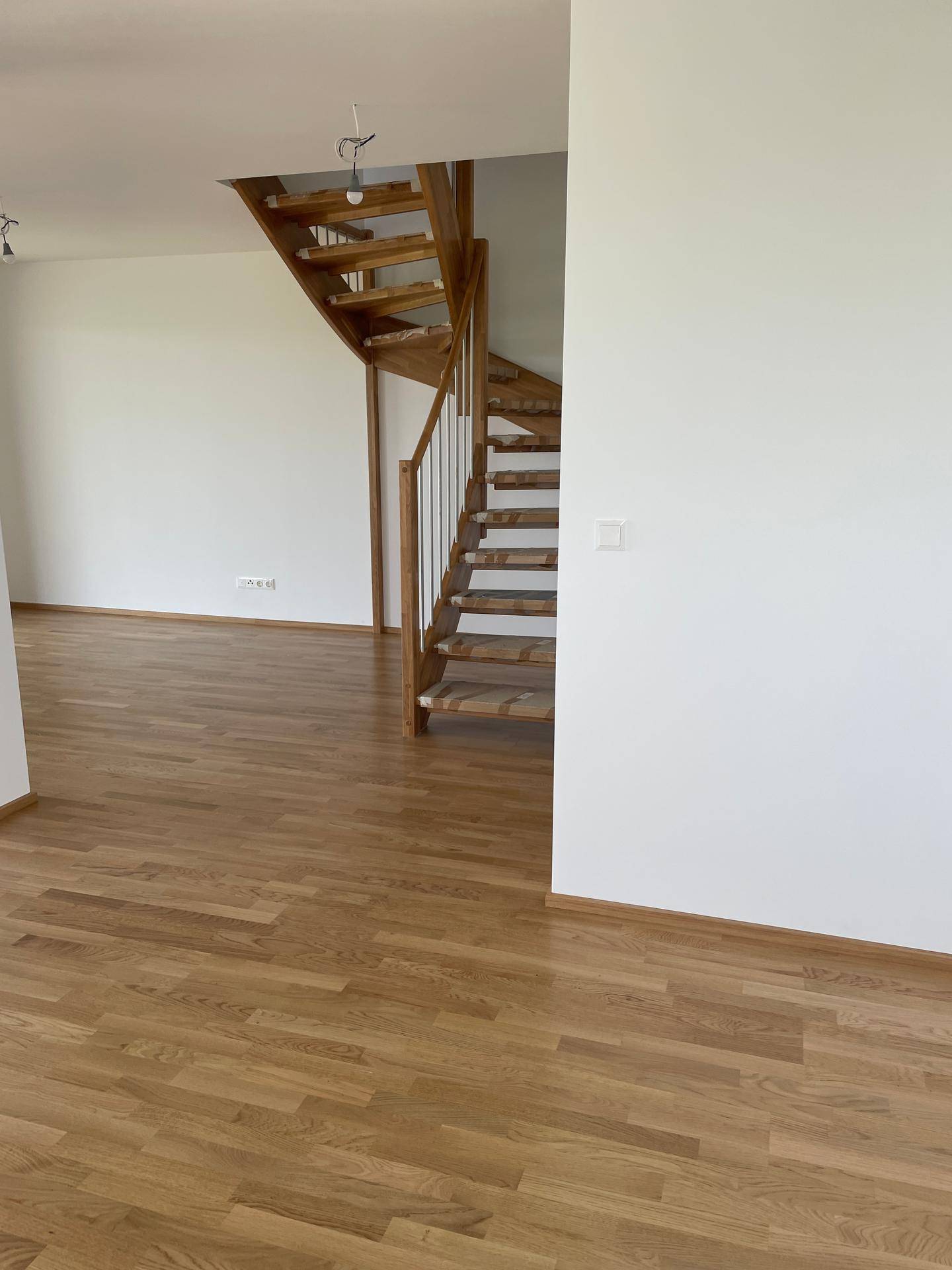 Moderne Holztreppe mit elegantem Metallgeländer, die die verschiedenen Ebenen des Hauses verbindet.