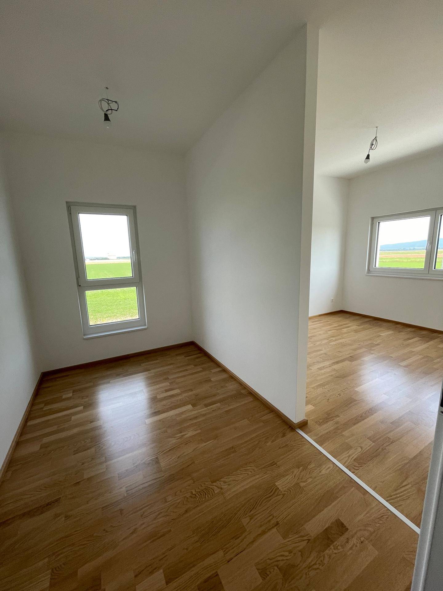 Zwei helle Räume mit Holzboden und Fenstern, die einen schönen Blick auf die Landschaft ermöglichen.
