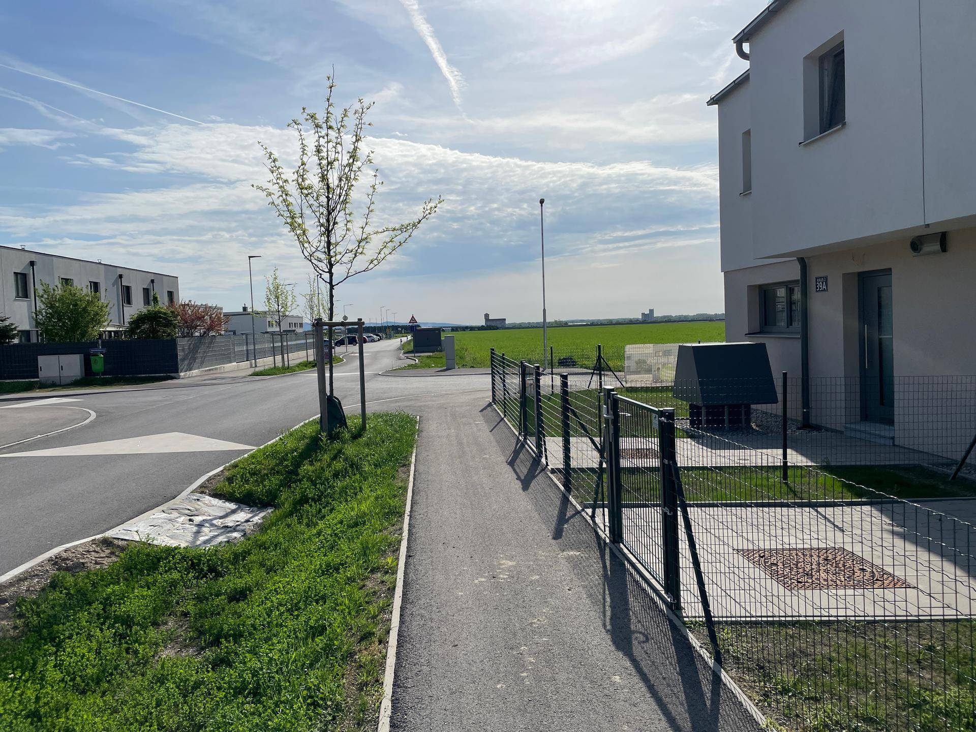 Außenansicht eines modernen Gebäudes mit Gehweg, Straße und weitem Blick ins Grüne.