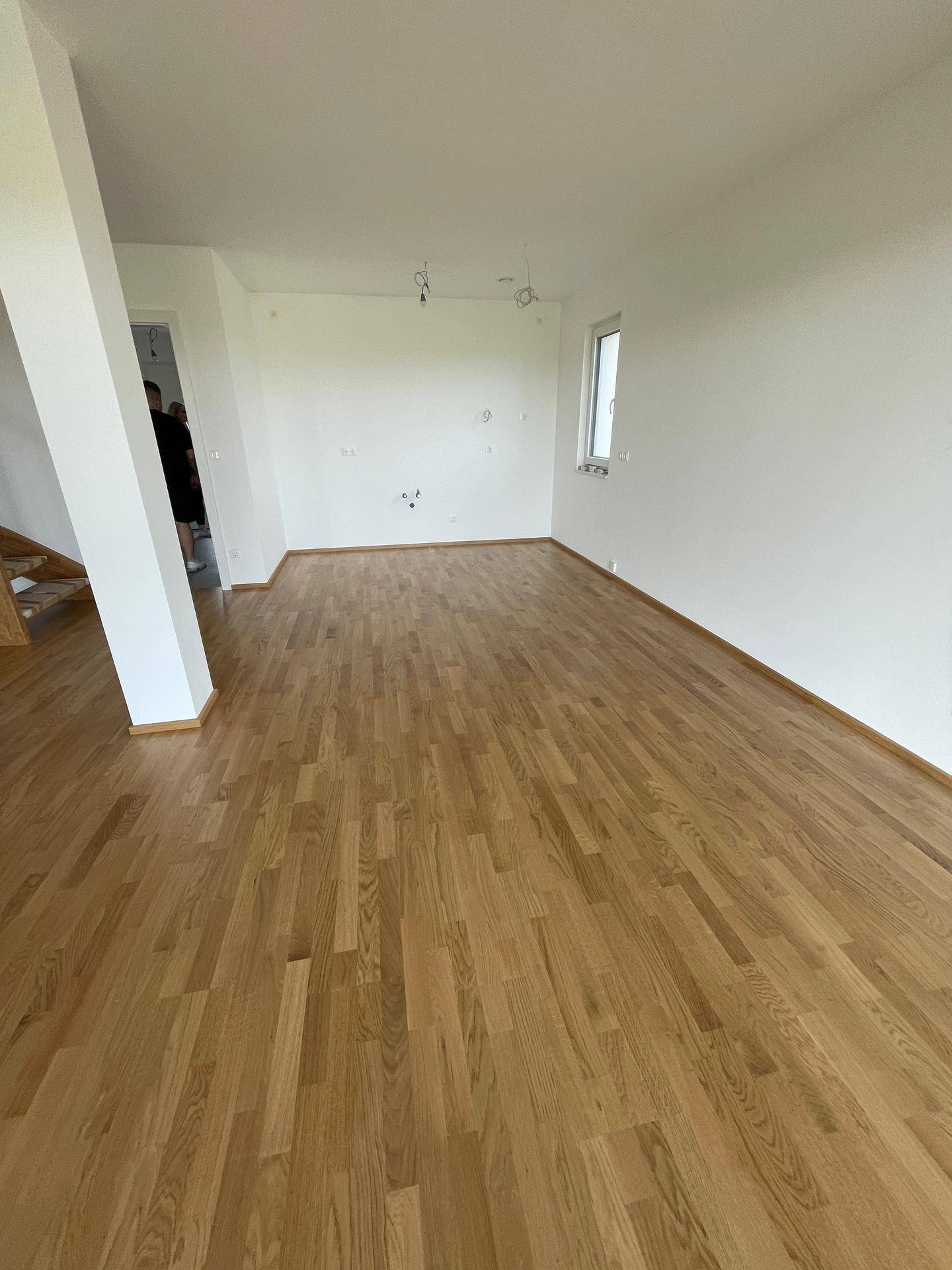 Heller, leerer Raum mit neuem Holzboden und weißen Wänden, bereit zur individuellen Gestaltung.