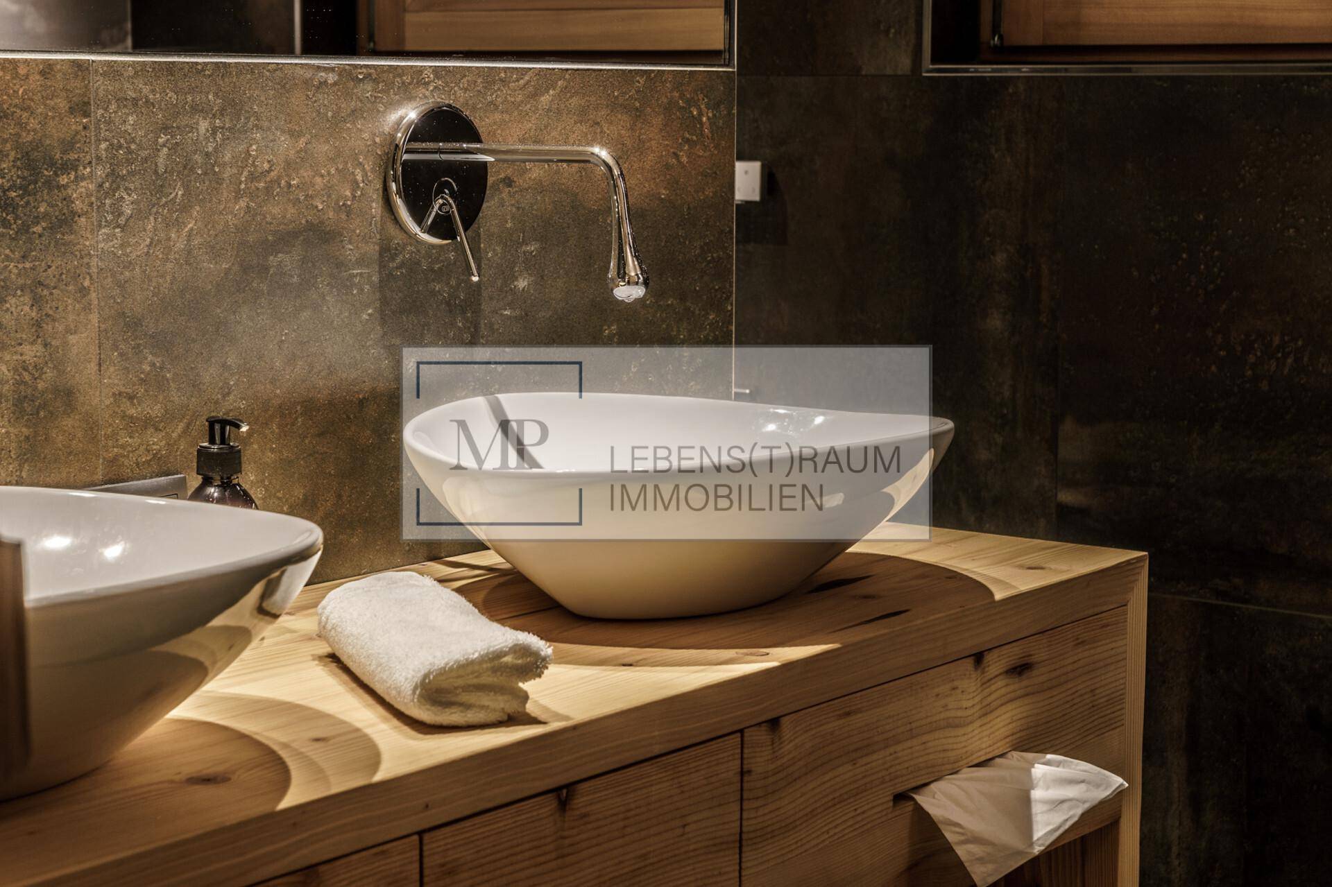 Modernes Badezimmer mit Holzwaschtisch, Aufsatzwaschbecken und dunklen Fliesen an der Wand.